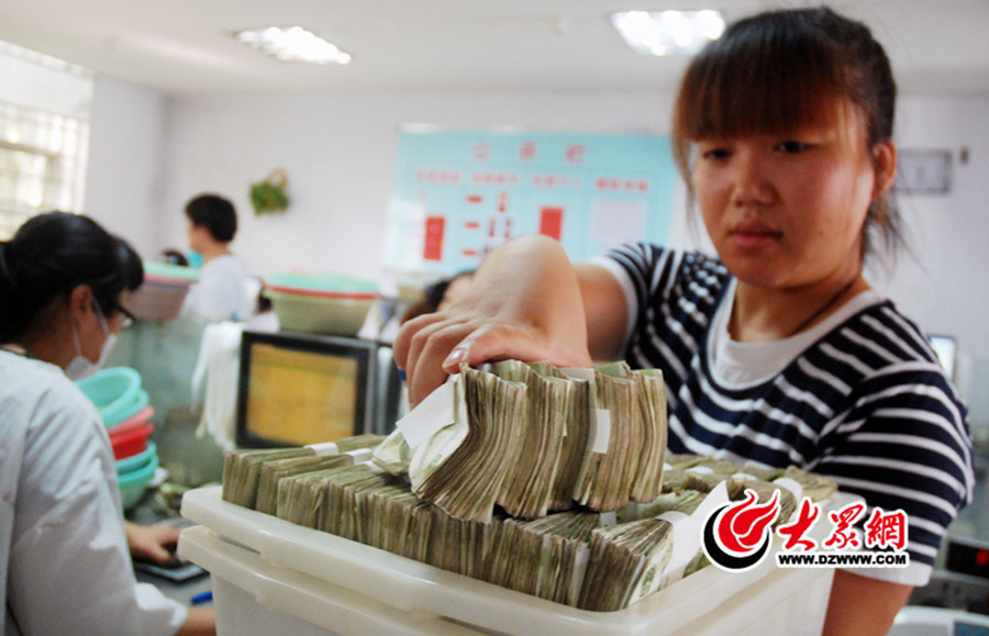 點鈔中心的龐燕忙著將各個點鈔員整理好的紙鈔收集進行機械捆綁。.jpg